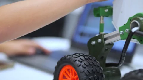 Child interacts with green and orange robotic vehicle Stock Footage 345022102