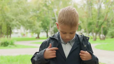 Child in jacket focusing on collar before heading to class. Young student 库存影片 338282987