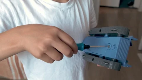 A child joyfully assembles a colorful toy with a small screwdrive Stock Footage 312466210