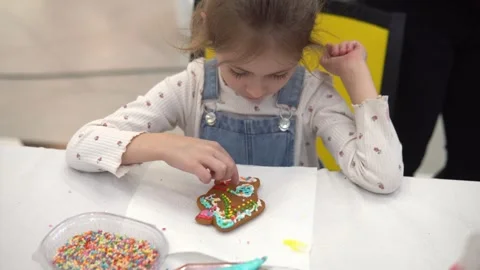 A Child Joyfully Decorating a Gingerbread Cookie with Colorful Sprinkles Stock Footage 280410130