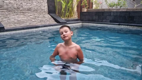 Child joyfully exercises in pool during holidays Lively pool setting adds to Stock Footage 266114949
