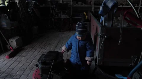 Child Joyfully Exploring in a Dimly Lit Workshop Setting Stock Footage 311781975