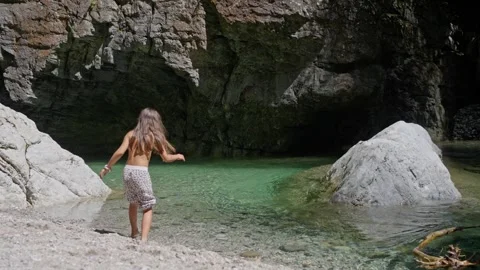 A child is joyfully exploring a tranquil natural pool nestled within a beautiful Video stock 314894294