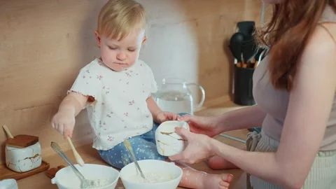 Child joyfully helps parent in kitchen with cooking activities Stock Footage 307134399