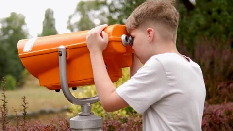 A child joyfully observing nature through an orange telescope Stock Footage 283466224