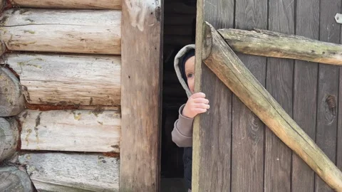 A Child Joyfully Peeking Out from the Rustic Cabin Door, Filled with Adventure Video stock 314710569