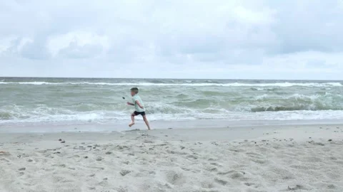A Child Joyfully Playing at the Beach with Splashes of Waves and Warm Summer Stock Footage 315859463