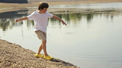 A Child Joyfully Playing Right By the Waters Edge During a Beautiful Summer Day Stock Footage 313333534