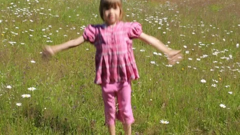 Child jumping on camomile field in summer morning Stock Footage