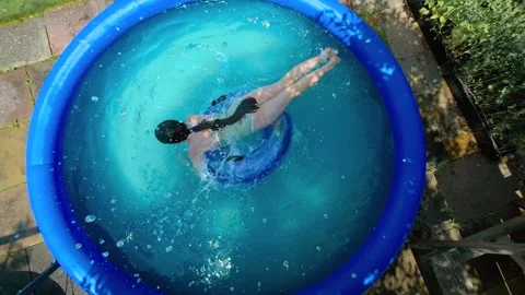 Child jumping on floating swim ring inside home inflatable pool during record Stock Footage 337880129