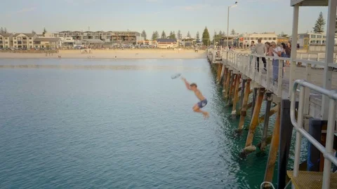Child jumping off Pier into the ocean at sunset, Adelaide, Australia Stock Footage 124935208