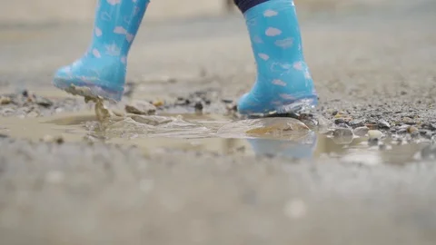 The child jumping in puddle with wellingtones Stock Footage 129691758
