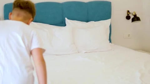 Child jumps on his back onto the bed Stock Footage 283524883