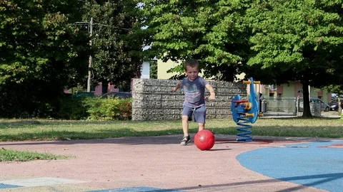 A child kicks a ball while playing at the playground Stock Footage 97752413