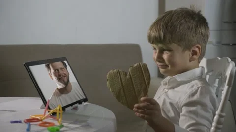 Child kid boy communicates on a tablet with a remote connection with his father Stock Footage 202010608
