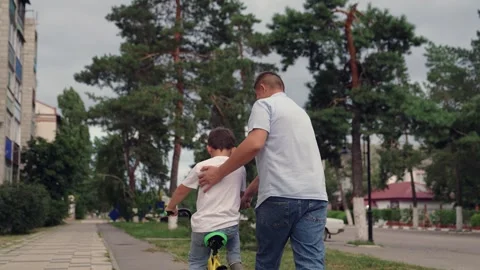 Child kid boy son learns ride bike, father teaches child kid boy son ride bike Stock Footage 302473254