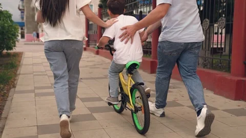 Child kid boy son learns ride bike, father teaches child kid boy son ride bike Stock Footage 314684178