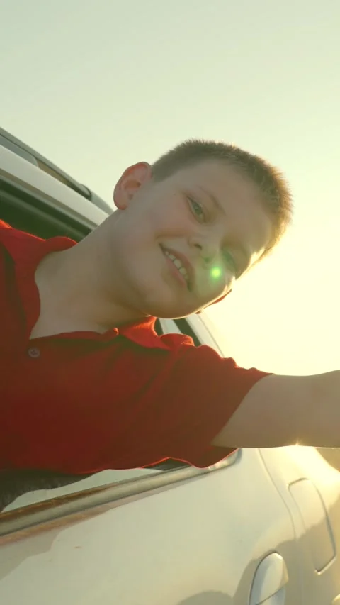 Child kid extends hand from car window, kid stuck head out window wind mixed Stock Footage 308319103