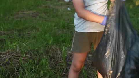 Child kid picking up plastic bottle in garbage bag. boy collect waste off in  Stock Footage 134638643