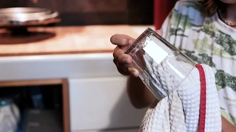 Child in the kitchen wiping with a cloth the items out of the dishwasher  Stock Footage 138437699