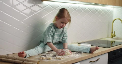 Child kneads dough on kitchen counter Stock Footage 333523942