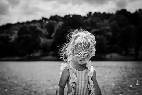 Child at lake in summer with windblown hair Stock Photos