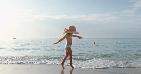 A child with a large straw hat on the seashore in summer. Video stock 167154167