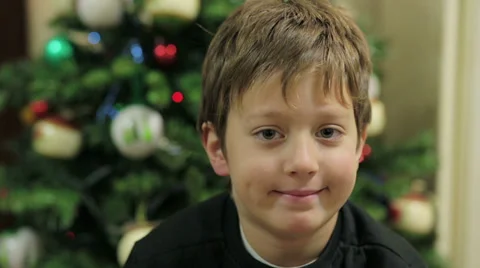 Child laughing and looking at the camera - christmas tree in the background Stock Footage 33404229