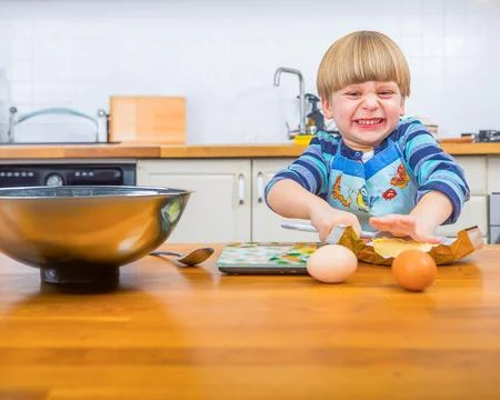 Child Laughing While Attempting to Bake in a Kitchen Setting Stock Photos