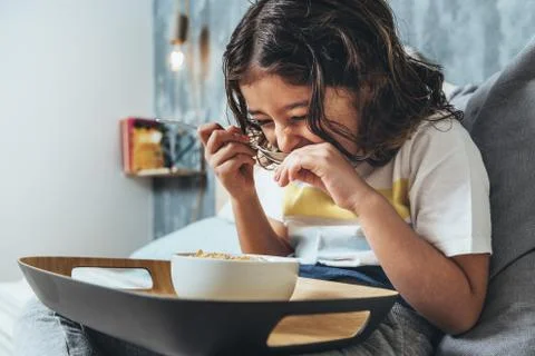 Child laughing while having a breakfast in the bed Stock Photos