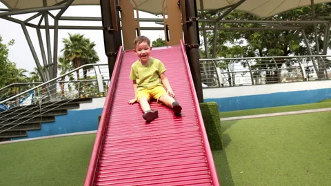 Child laughs happily, slides down children's slide in children's park,Little boy Stock Footage 182459222