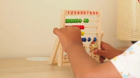 Child learning to count on a wooden abacus, engaging in educational play ac.. Video stock 332041352