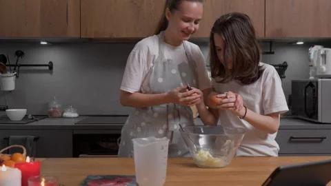 Child learning to crack an egg makes a funny mistake while baking with mom. Stock Footage 311806977