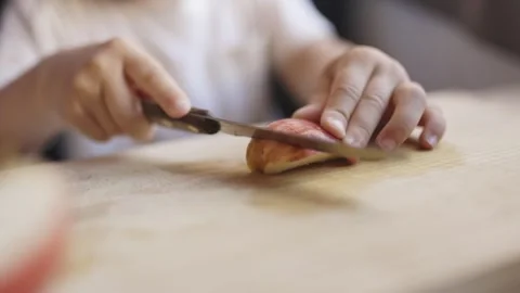 Child learning to cut apple with mothers help Stock Footage 319154126