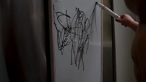Child learning to draw. Scribbling with marker on white board. Stock Footage 255319735