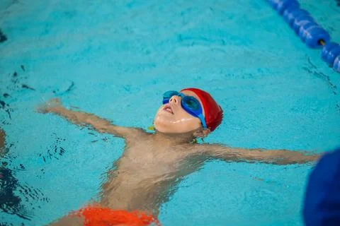 Child learning to float on back in pool Stock Photos
