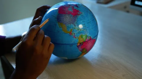 Child learning geography with a world globe, Child's hands use a pencil to .. Video stock 346463250