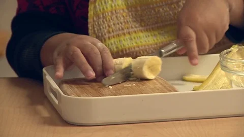 A child learning how to cut a banana in a Montessori School Class  Stock Footage 83225017