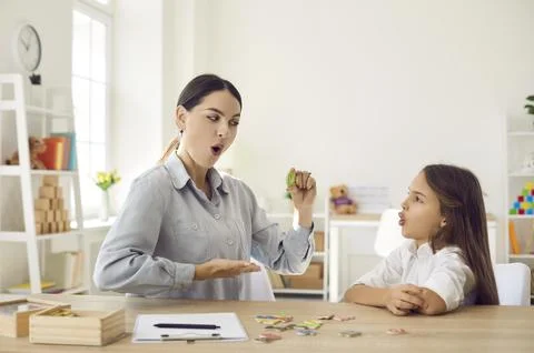 Child learning letters and doing articulation exercise together with speech Stock Photos