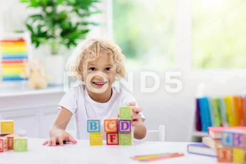 Child learning letters. Kid with wooden abc blocks Stock Photos