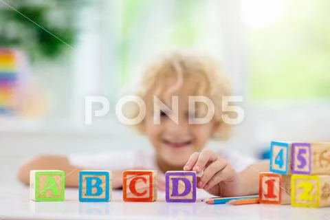Child learning letters. Kid with wooden abc blocks Stock Photos