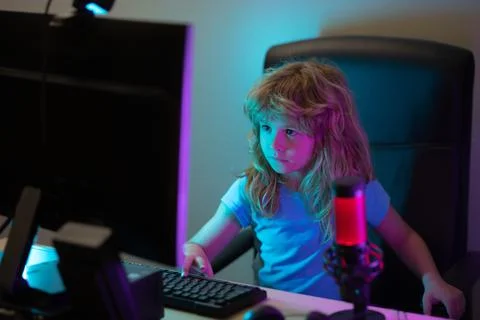 Child learning online at night, using desktop computer in living room at home Stock Photos