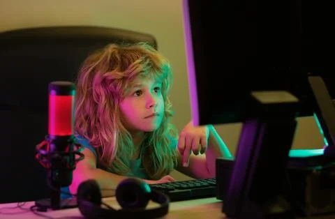 Child learning online at night, using desktop computer in living room at home Stock Photos