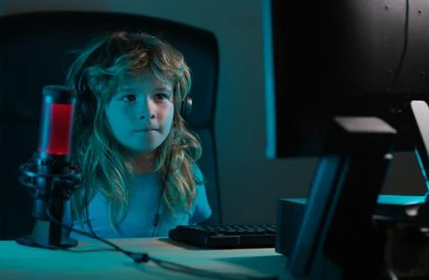 Child learning online at night, using desktop computer in living room at home Stock Photos