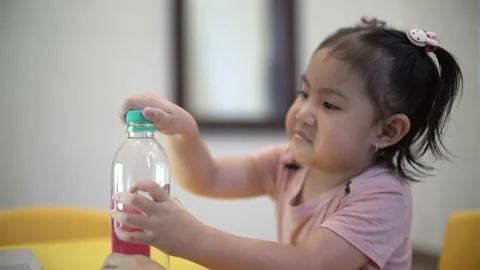 Child learning to open a bottle cap for basic life skill Stock Footage 158951168