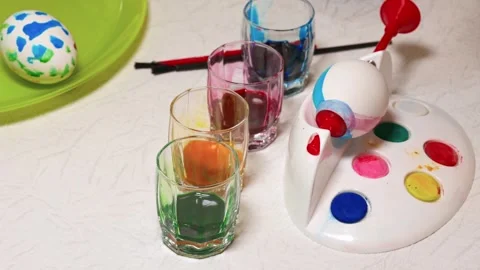 Child learning to paint Easter egg using special stand with watercolor palette Stock Footage 303862462