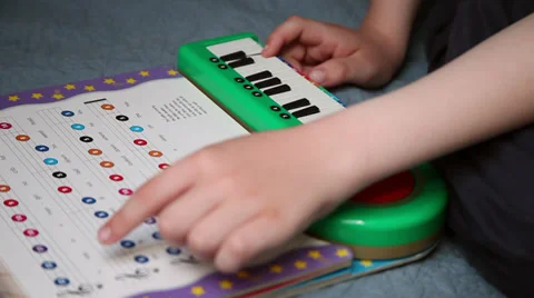 Child learning to play music, practicing, keyboard, following musical notes,book Stock Footage 37389061