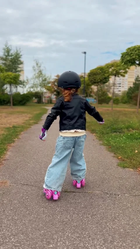 Child learning to roller skate in an urban park Stock Footage 345634013