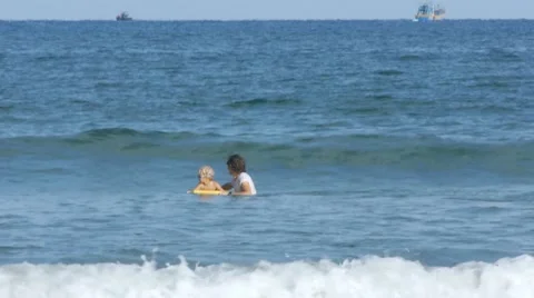 Child learning to surfboard the waves on bodyboard with farther,enjoying sea Stock Footage 55883078