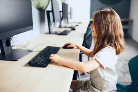 Child learning to use technology in classroom at primary school. Schoolgirl.. Stock Photos